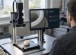 KI-Implementierung: Ein Qualitätsprüfer vergleicht ein rissiges Bauteil mit der KI-Auswertung im Pilotbetrieb.