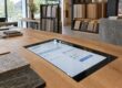 KI-Leadgenerierung: Ein CRM-Bildschirm im Materialshowroom zeigt eine KI-geprüfte Anfrage mit Übergabe an den Vertrieb.